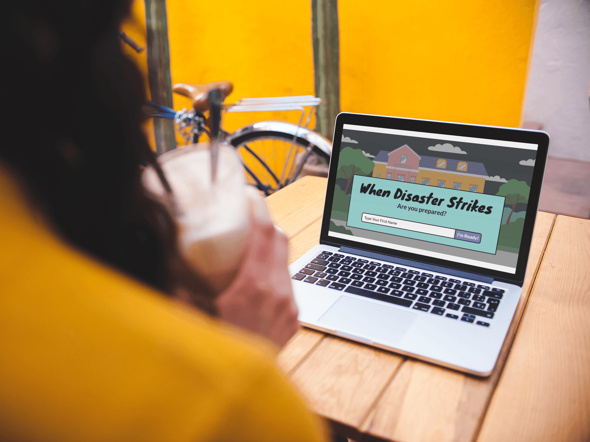 The When Disaster Strikes title screen shown on a laptop in a cafe