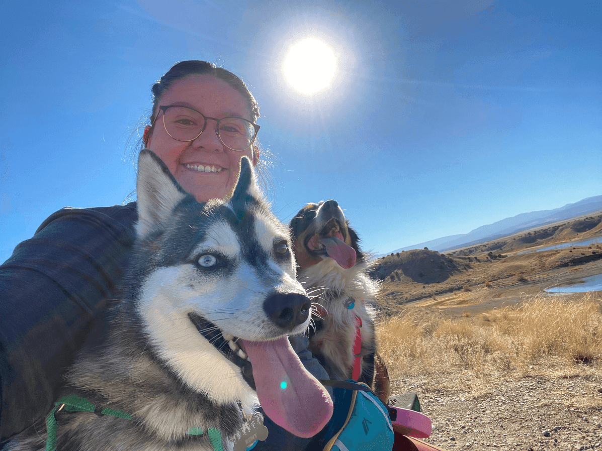 Sabrina hiking with her two dogs under a bright sun